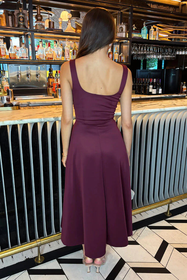 Woman in a purple dress standing in a bar setting