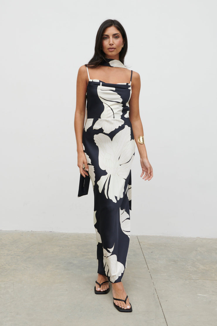 Woman wearing a black and white floral dress against a plain background