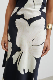 Woman wearing a black and white patterned jumpsuit against a plain background