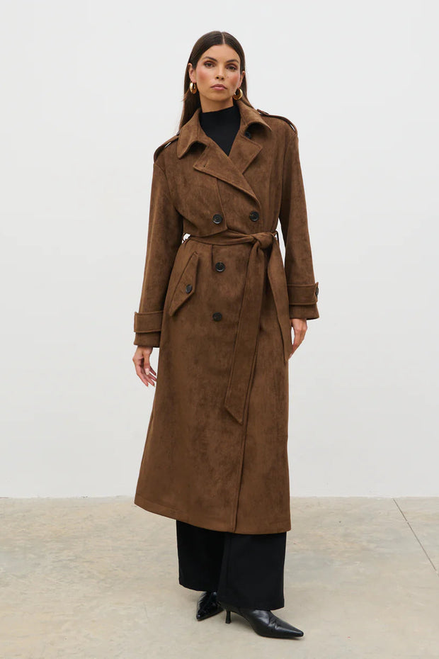 Woman wearing a brown trench coat against a white background