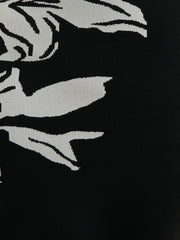 Black fabric with white embroidered design of a stylized face and hands.