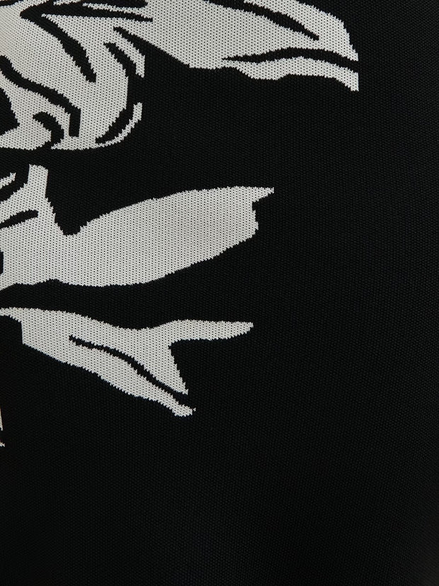 Black fabric with white embroidered design of a stylized face and hands.
