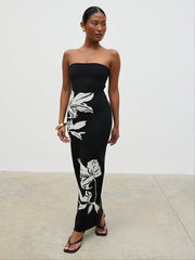 Woman wearing a black strapless dress with white floral patterns on a light gray background