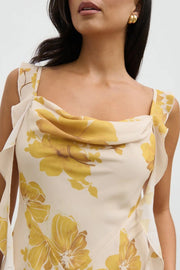 Woman wearing a yellow floral dress against a white background