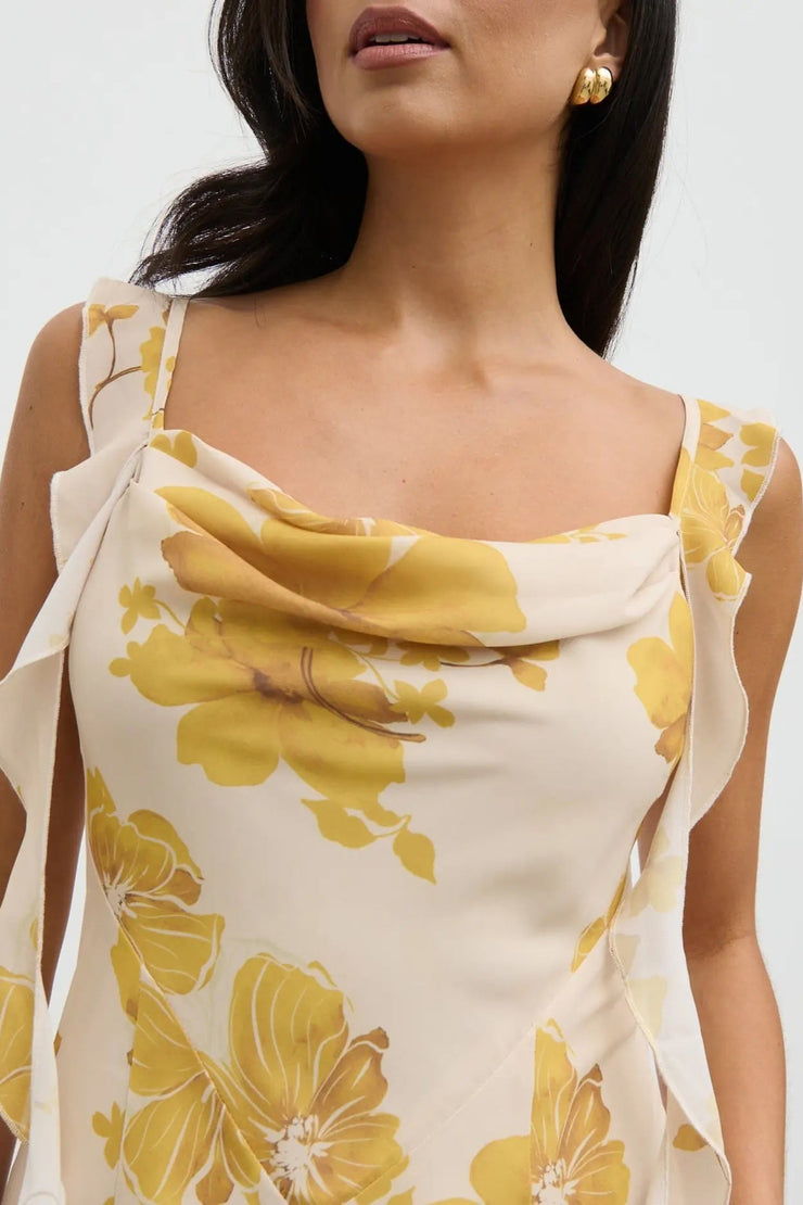 Woman wearing a yellow floral dress against a white background