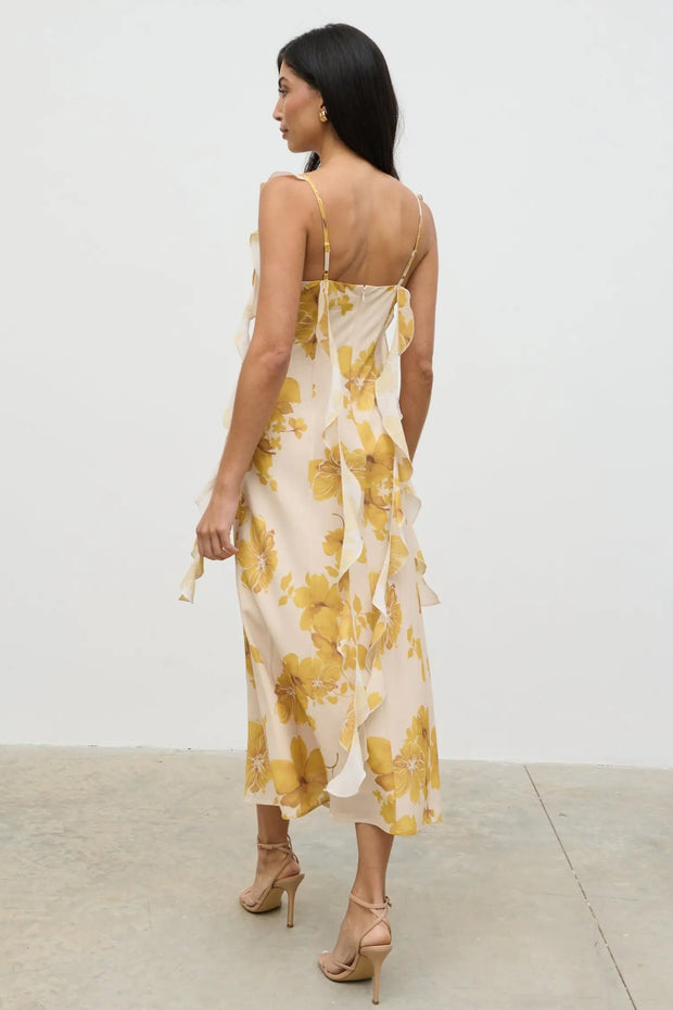 Woman wearing a yellow floral dress against a white background