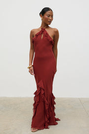 Woman wearing a burgundy evening gown with ruffled details against a white background