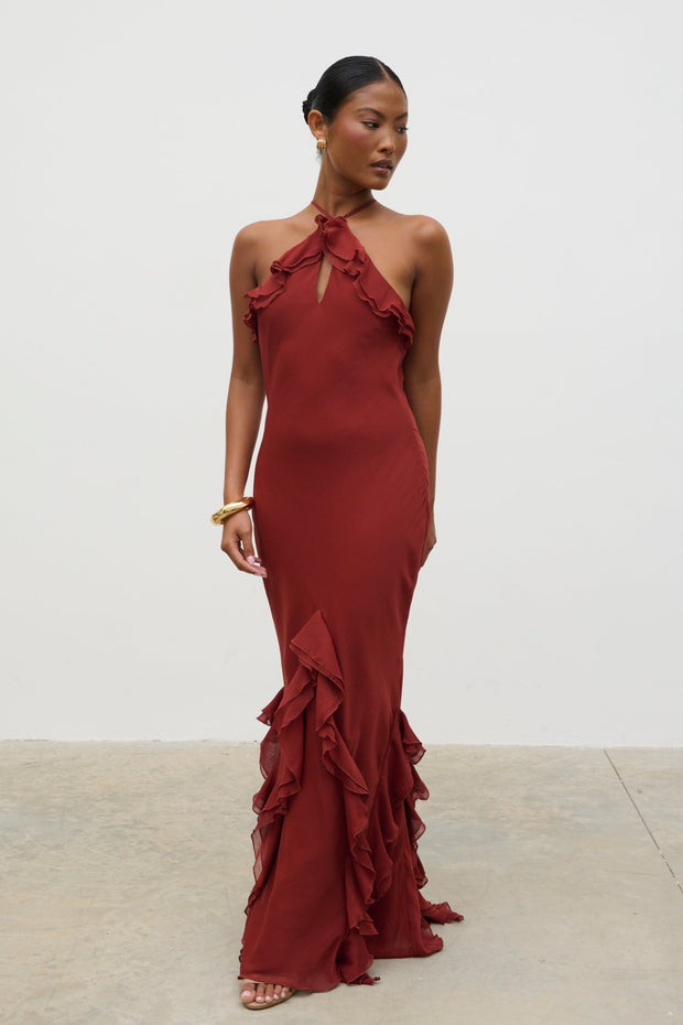 Woman wearing a burgundy evening gown with ruffled details against a white background