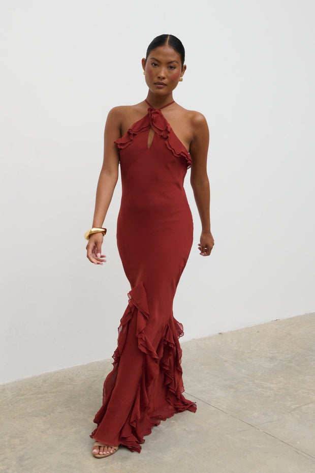 Woman wearing a red evening gown with ruffled details against a white background