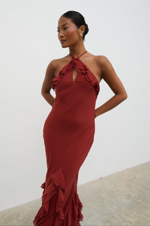 Woman wearing a red evening gown with ruffled details against a white background